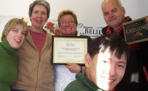 Two literacy participants, Sarah, and Danh help Cheryl present a certificate of appreciation to Banan and Roger Pattison