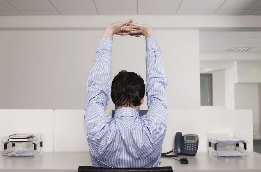 A man stretching at his desk