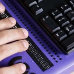 Hands typing on a Braille keyboard