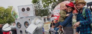 Maker Faire attendees; foreground: a man and a woman with a child, smiling