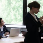 A woman using her phone at work with a man looking away in the background