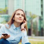 Woman sitting outside with earphones plugged in