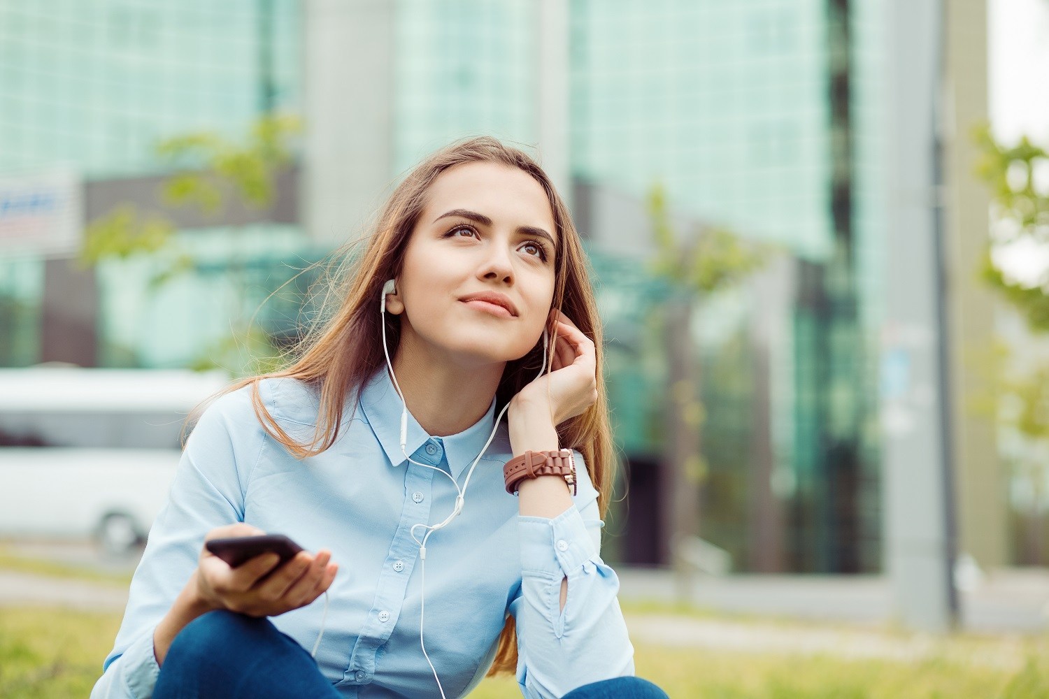 Woman sitting outside with earphones plugged in