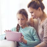 Girl using an iPad, with woman sitting next to her