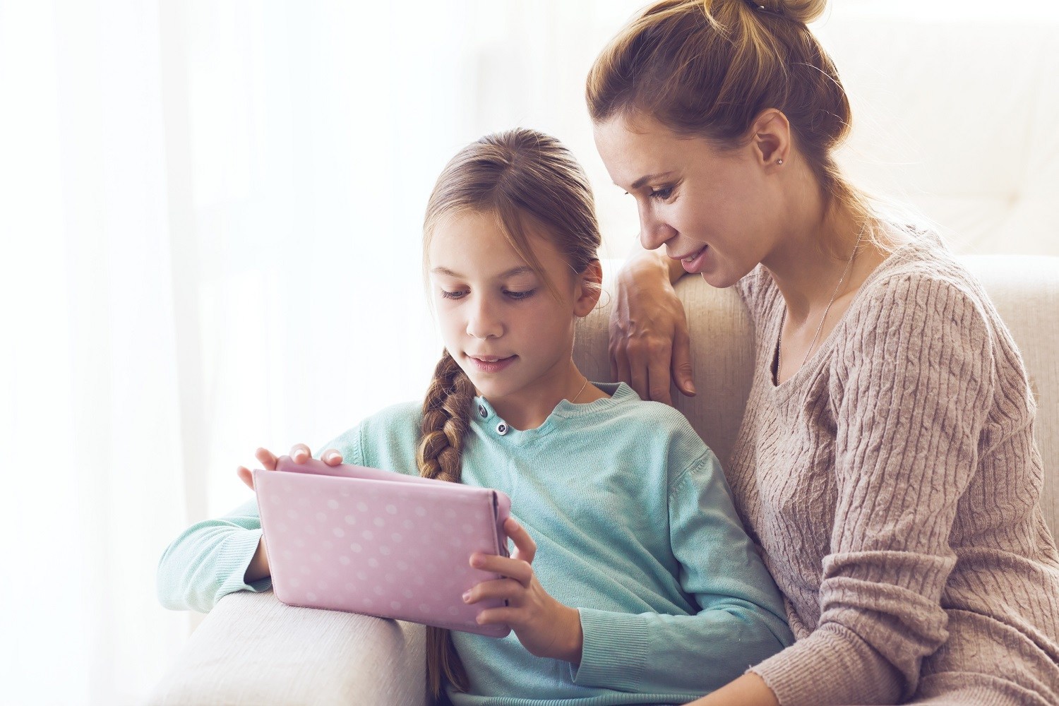 Girl using an iPad, with woman sitting next to her