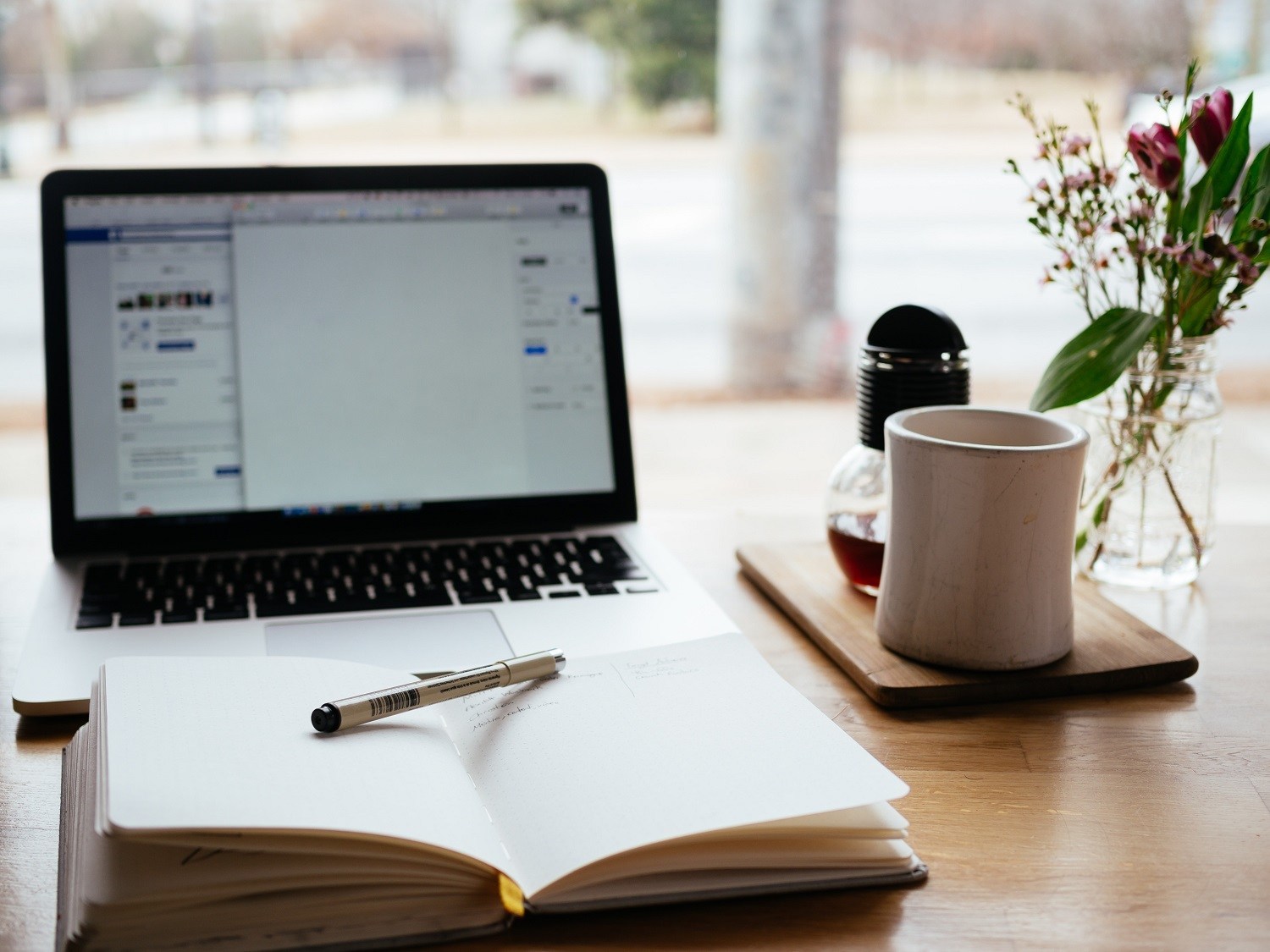 a laptop with a notebook and pen in front of it