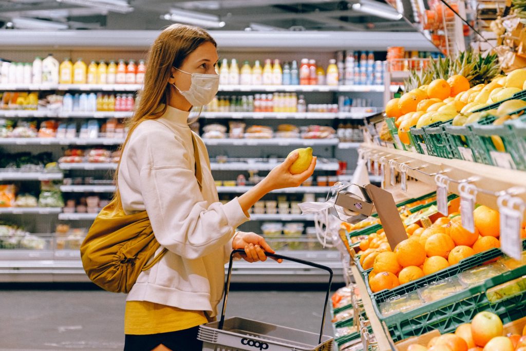 stock image of woman in supermarket holding up fruit