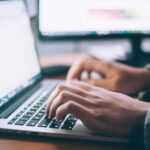 close-up of person typing at a laptop