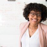 woman smiling; behind her is a whiteboard