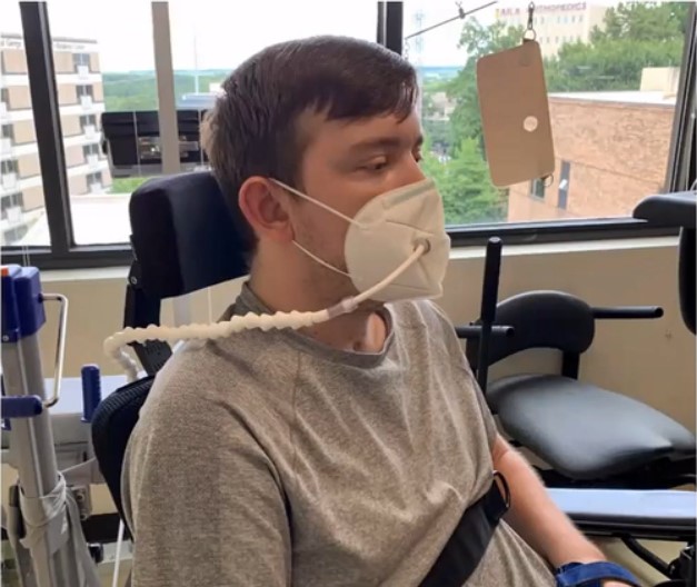 teenager wearing a medical mask with a tube coming out of it