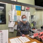 Working Together participant Patty working behind the counter, wearing a mask and behind plexiglass