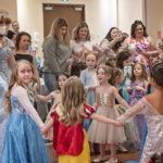 little girls in princess costumes dance with a Storybook Princess at the 2022 Princess Ball