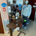 Marla Calder standing in front of a small movable table with various assistive technology