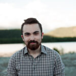 Scott smiling into the camera with a mountain and lake in the background