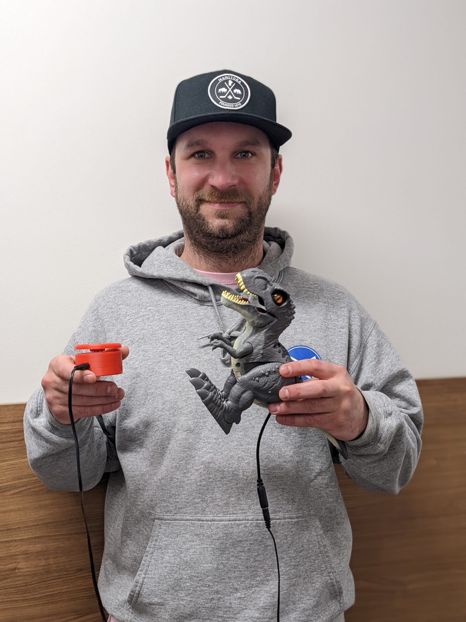 a Movement Centre employee holding up a switch adapted T-rex toy