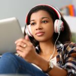 a woman holding a tablet while wearing headphones