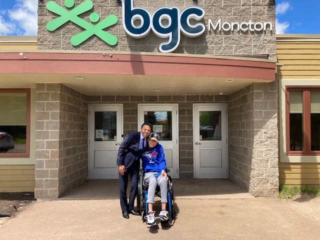 Adam in a wheelchair with BGC Moncton Executive Director Moncef Lakouas outside the BGC Moncton building