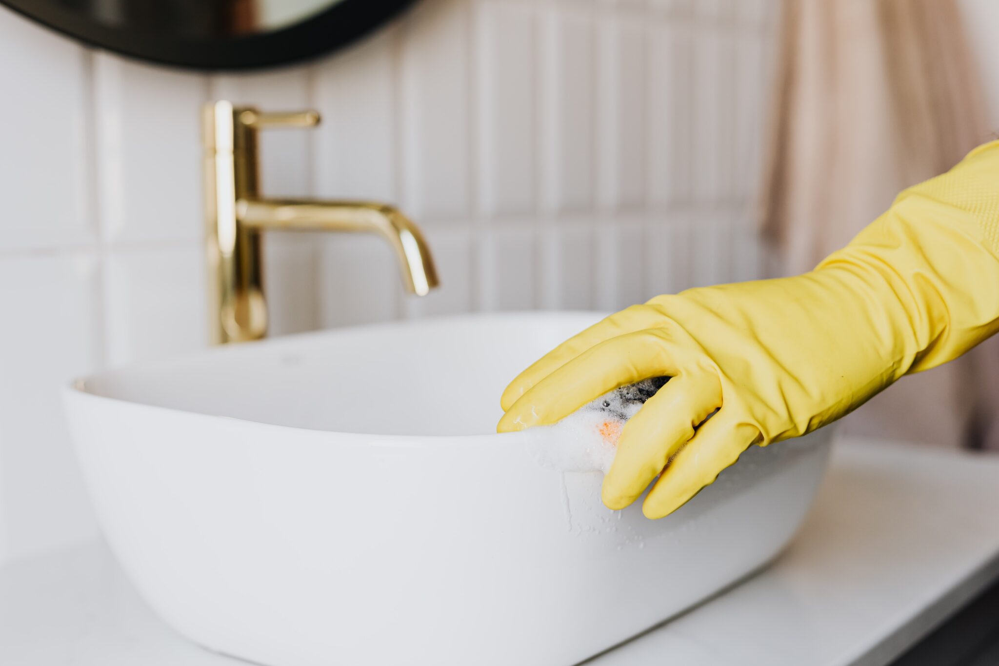 person wearing a glove cleaning a bathroom sink