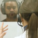 Tyson Gillies in a sound booth getting a hearing test from audiologist Heather