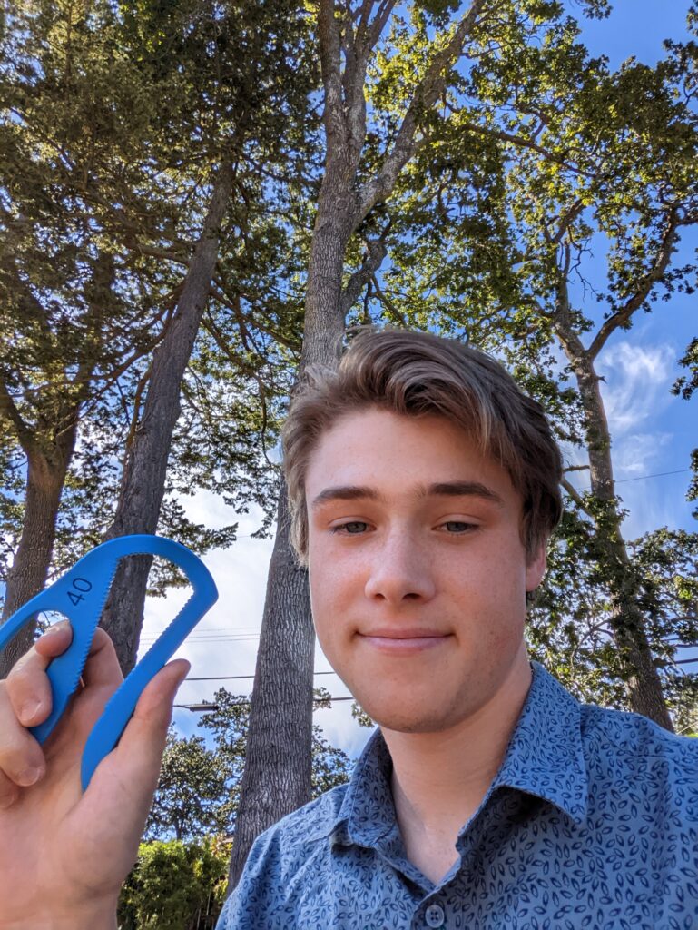 MMC intern Taz showing off the re-designed Bottle Opener while standing in front of some trees outside