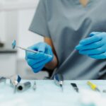 a person wearing gloves and dental scrubs grabs some dental tools