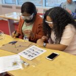 two women working together to build a device