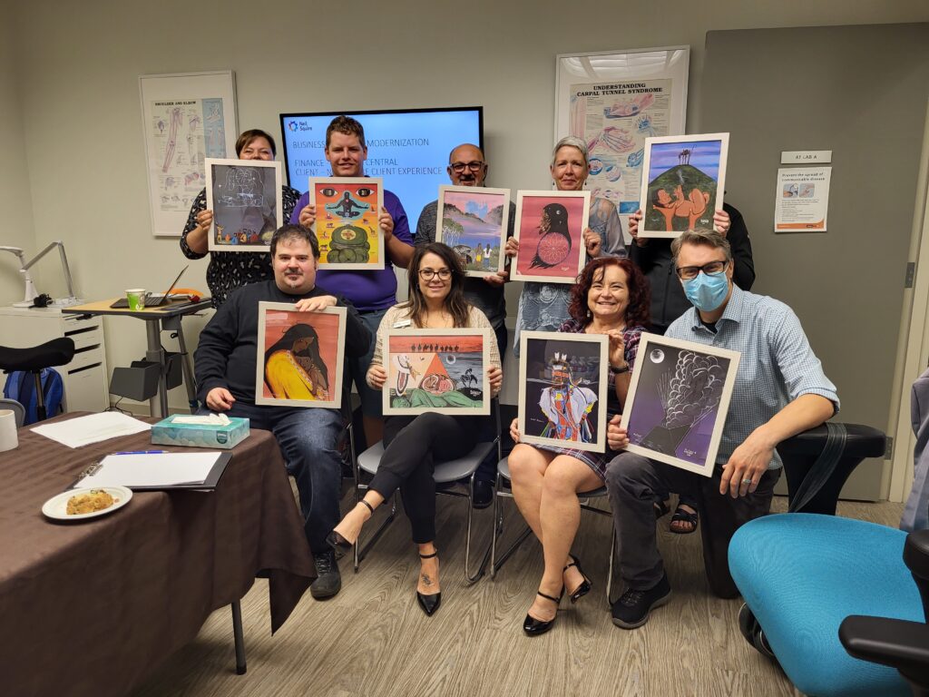 Neil Squire staff posing together holding Ron's works of art