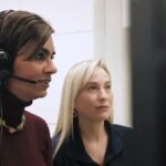 a woman in a headset uses a computer as a Neil Squire employee watches on