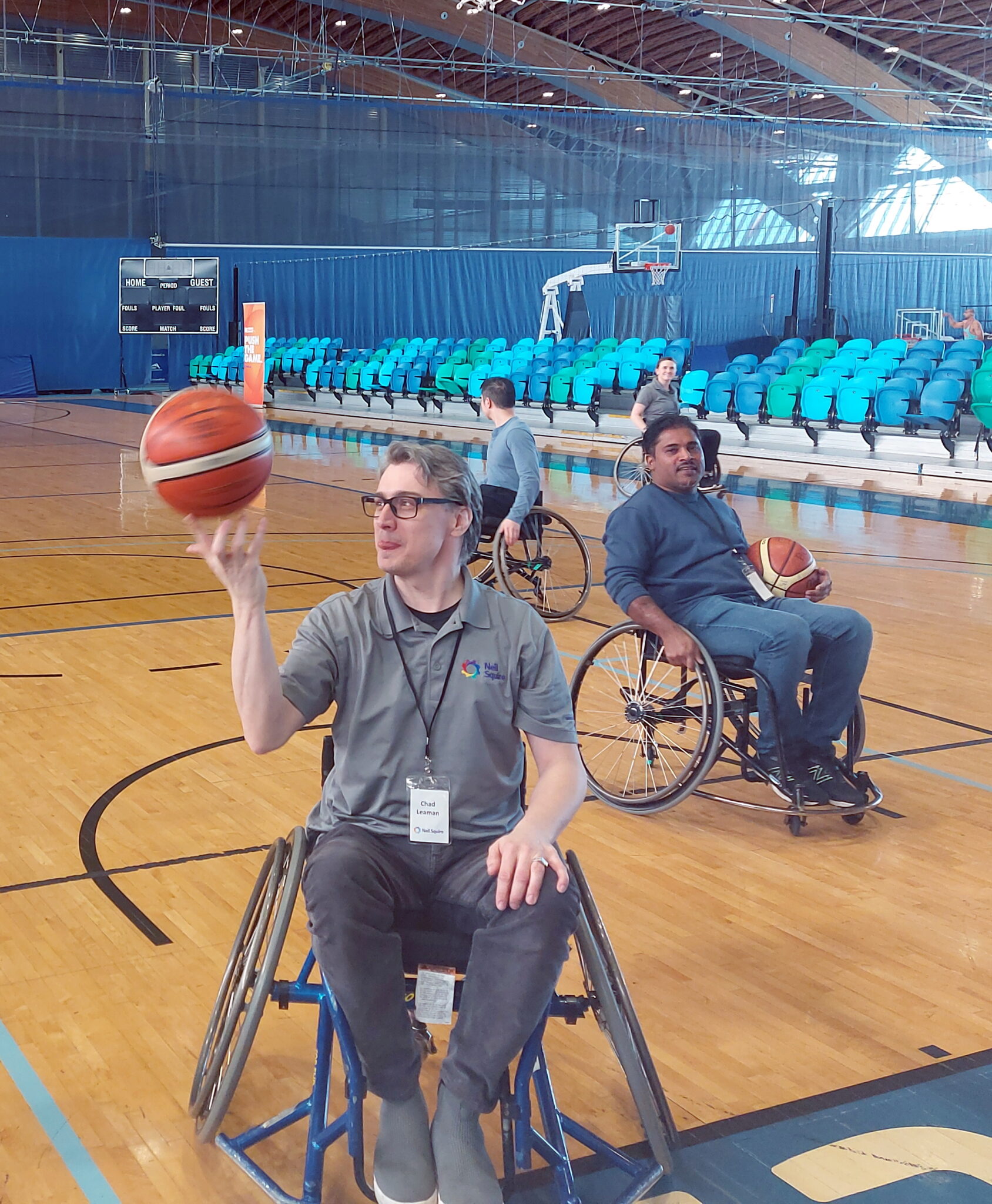 Neil Squire staff play wheelchair basketball, as Chad spins a basketball in his hand