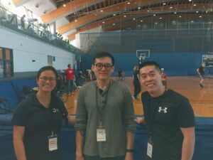 Our Working Together representatives Stephanie, Kakie and Louis smile for a group photo in front of the basketball court