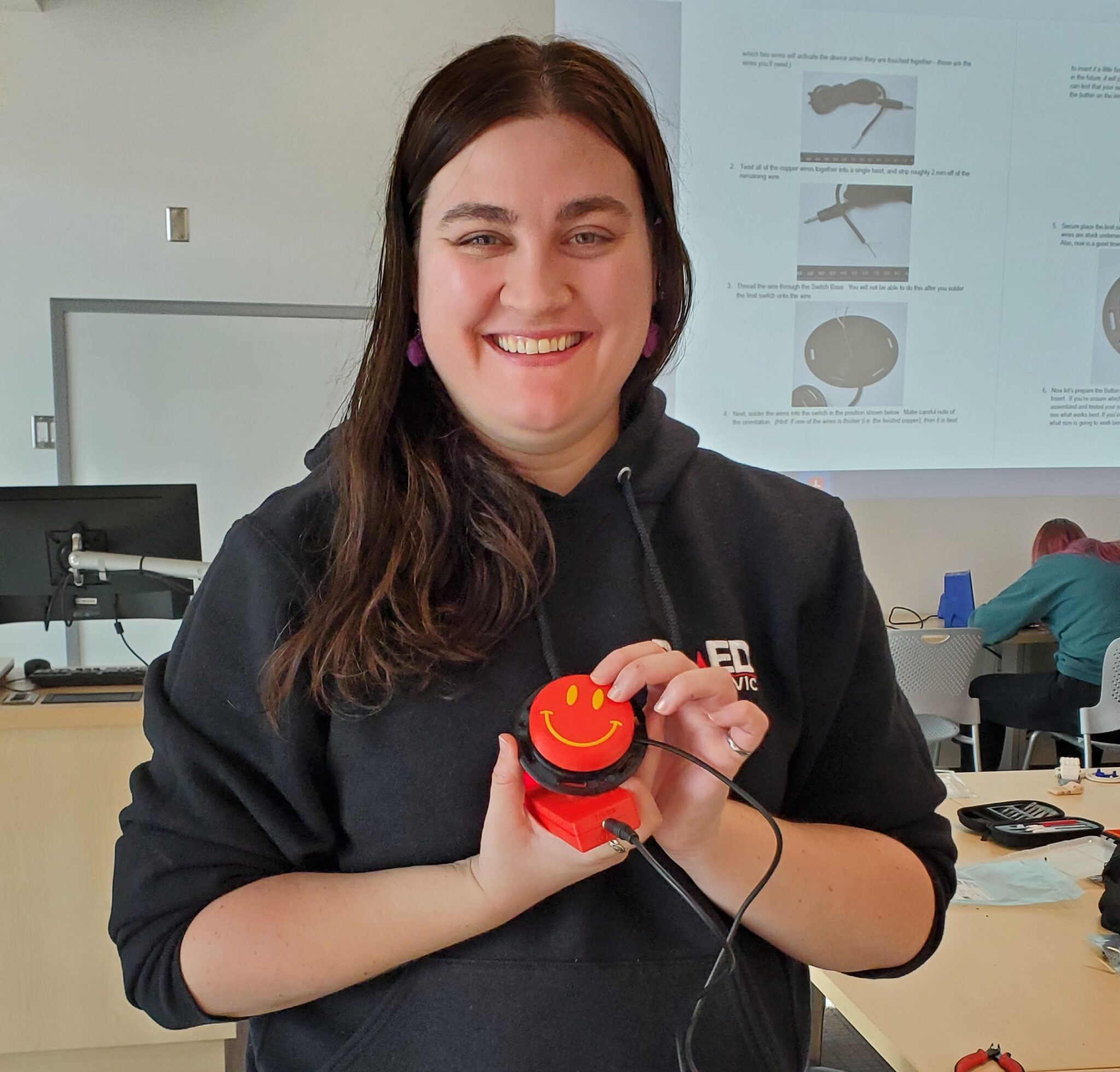 a student shows of their Interact Switch that they made with a smiley face on the button