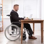 a man in a wheelchair using a laptop