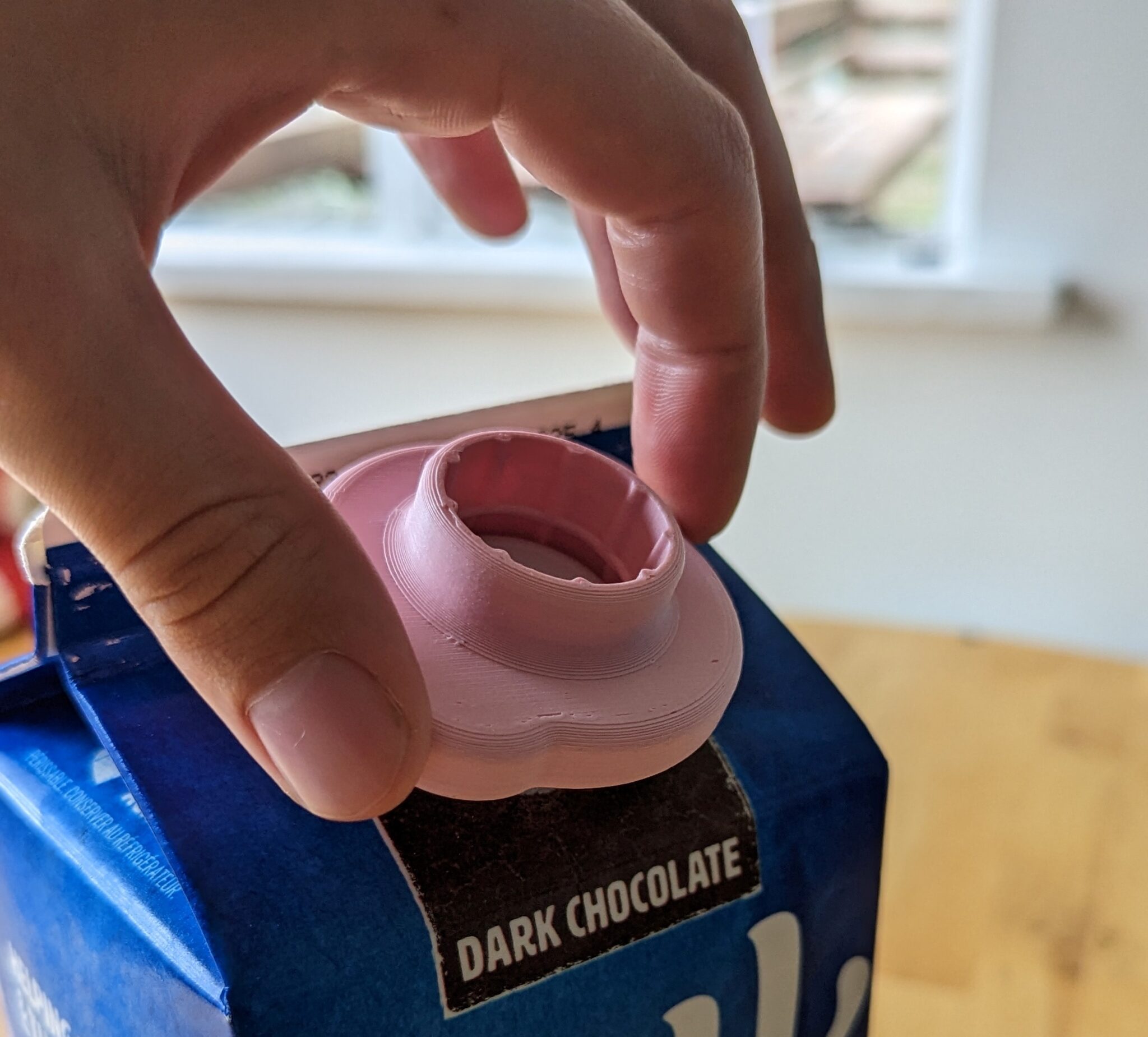 a person using a Milk Carton Opener to take off the cap on a 2-litre soy milk carton