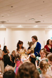 Performers dressed as Beauty and the Beast dance with a girl