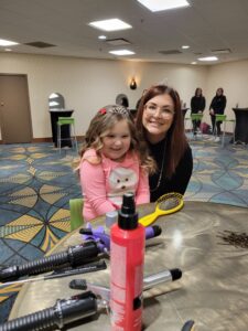 a child smiles with her hairdresser as she gets her hair done