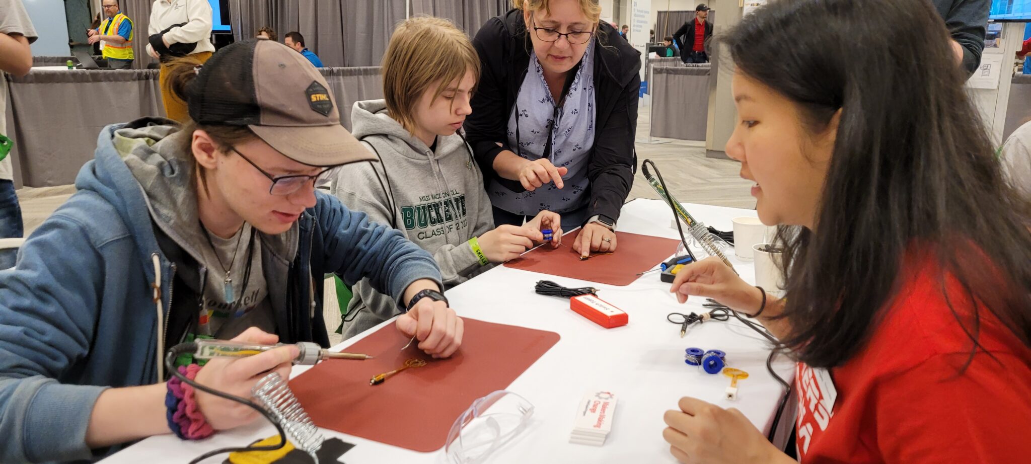 Makers Making Change staff member Kristina walks students through soldering.