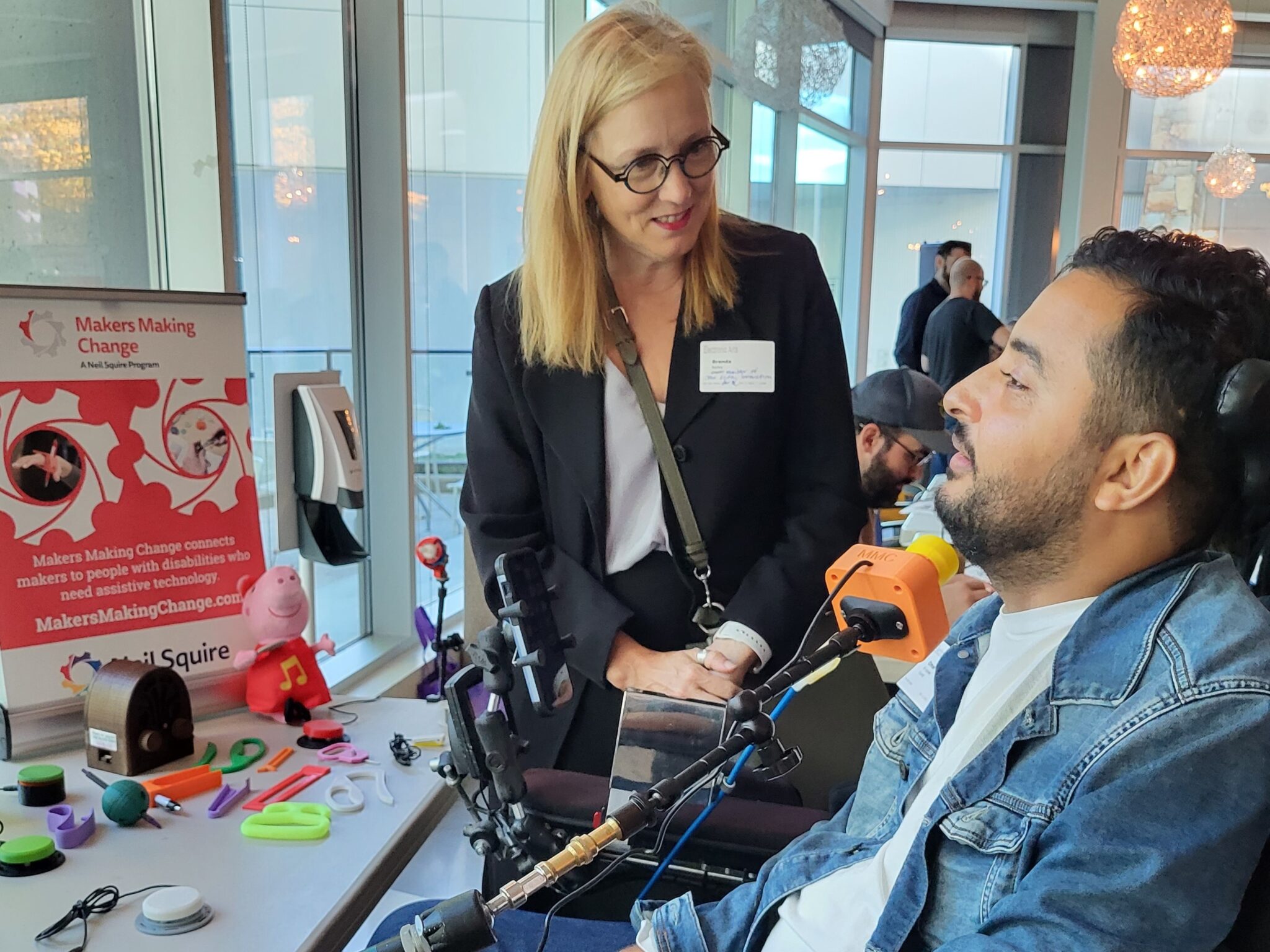 Brenda Bailey, the BC Minister of Jobs, Economic Development and Innovation talks with a gamer in a wheelchair, as he tests out the joystick.