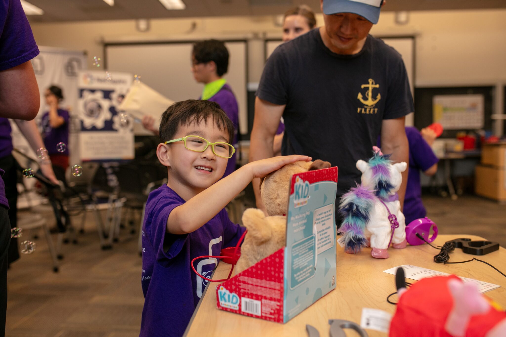 A child touches an adapted toy while an adult watches over.