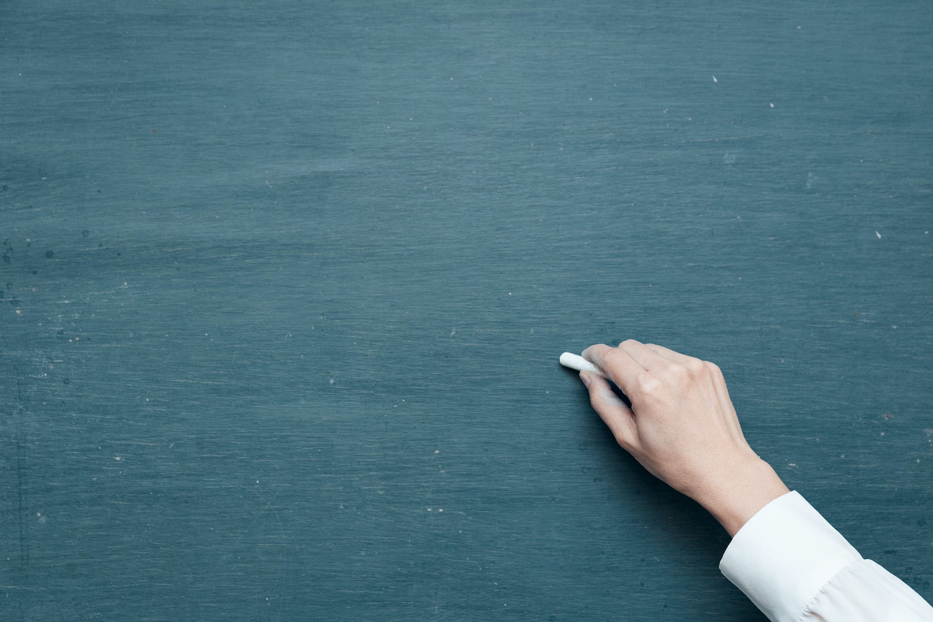 A person writing on a chalkboard.