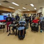 West Park staff, patients, and MMC staff pose together with the adaptive gaming equipment at West Park.