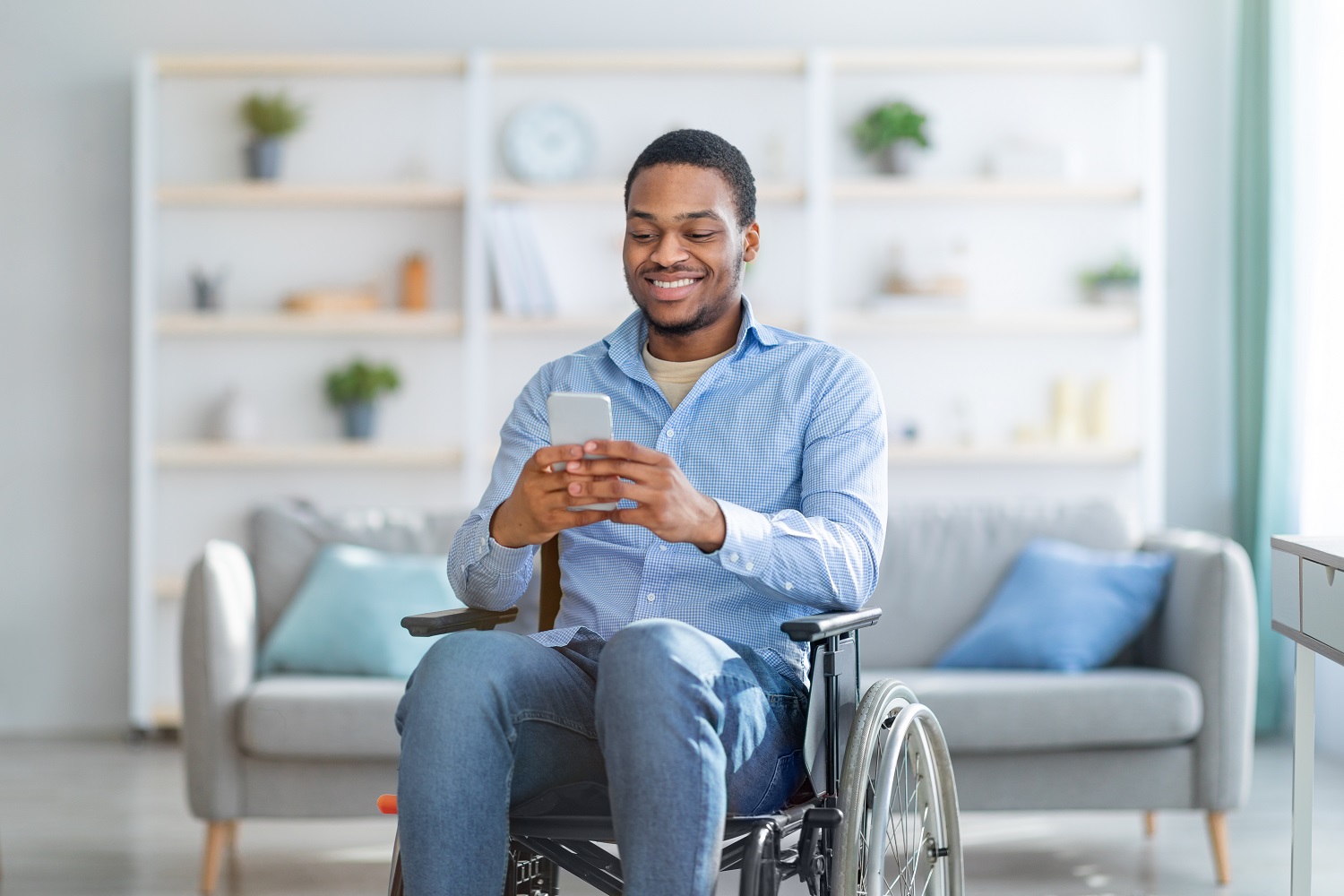 A man in a wheelchair smiles while he uses his phone.