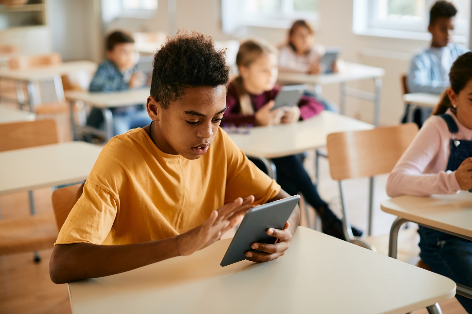 A boys uses a tablet in the classroom.