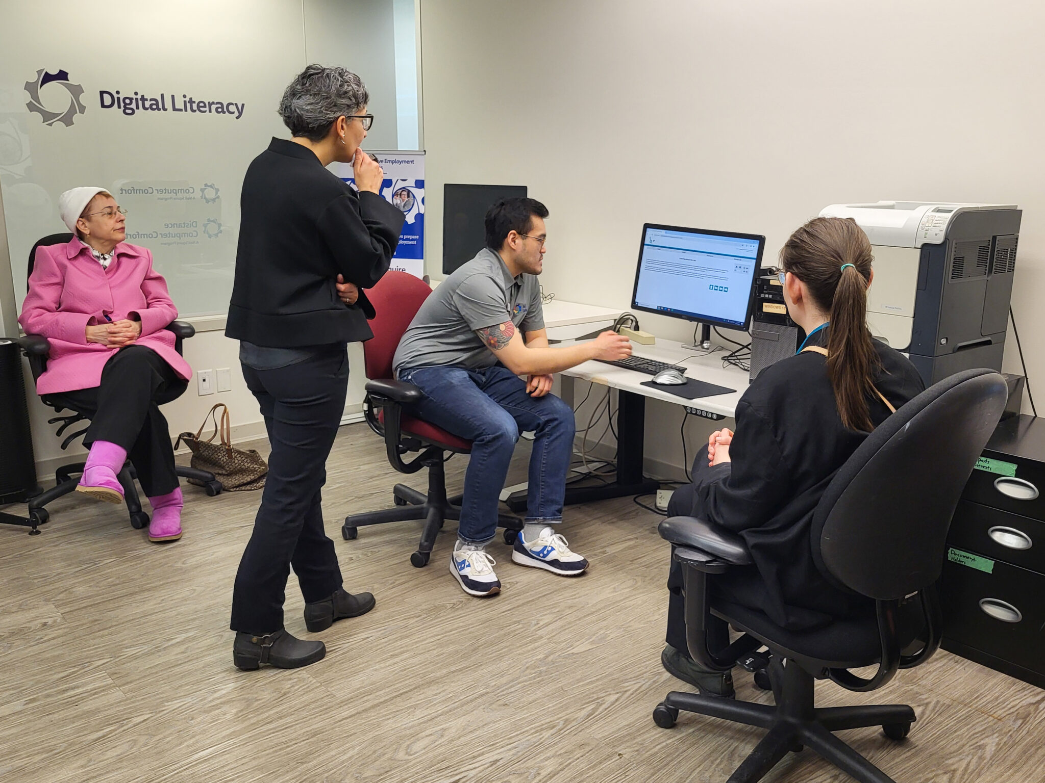 Senior Case Manager Kakie Wong demonstrates a learning platform to Nisa Tummon and Creative Employment Options participants.