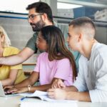 A male teacher helps a group of his students.