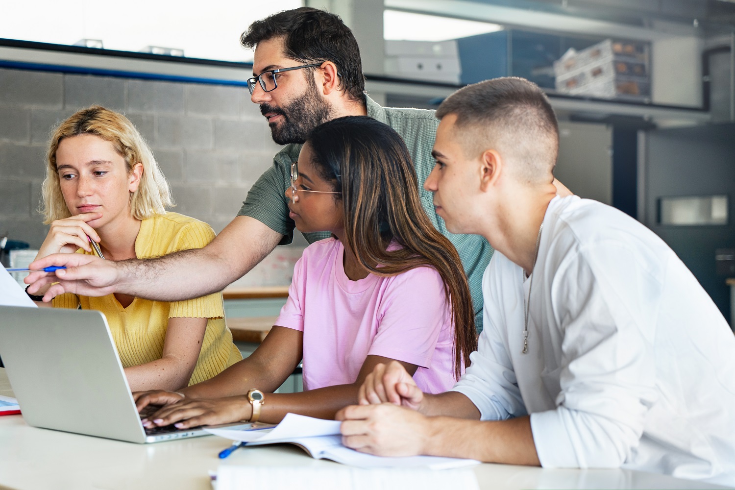 A male teacher helps a group of his students.