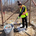 Malachi picking up garbage, while wearing a high vis vest.