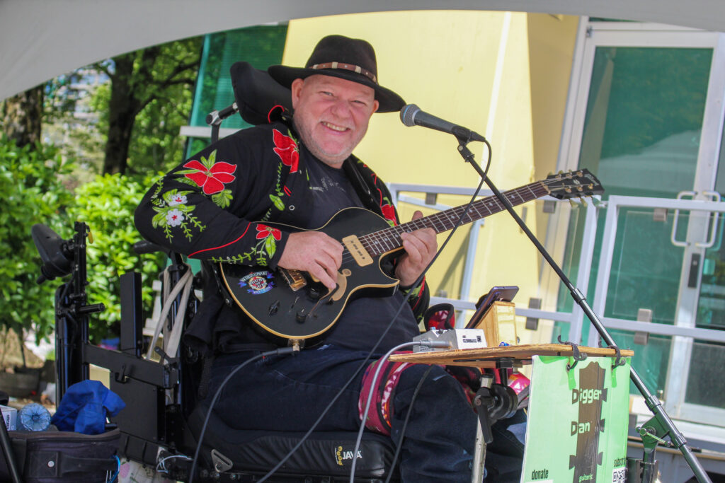 Digger Dan, in a wheelchair, playing his guitar.