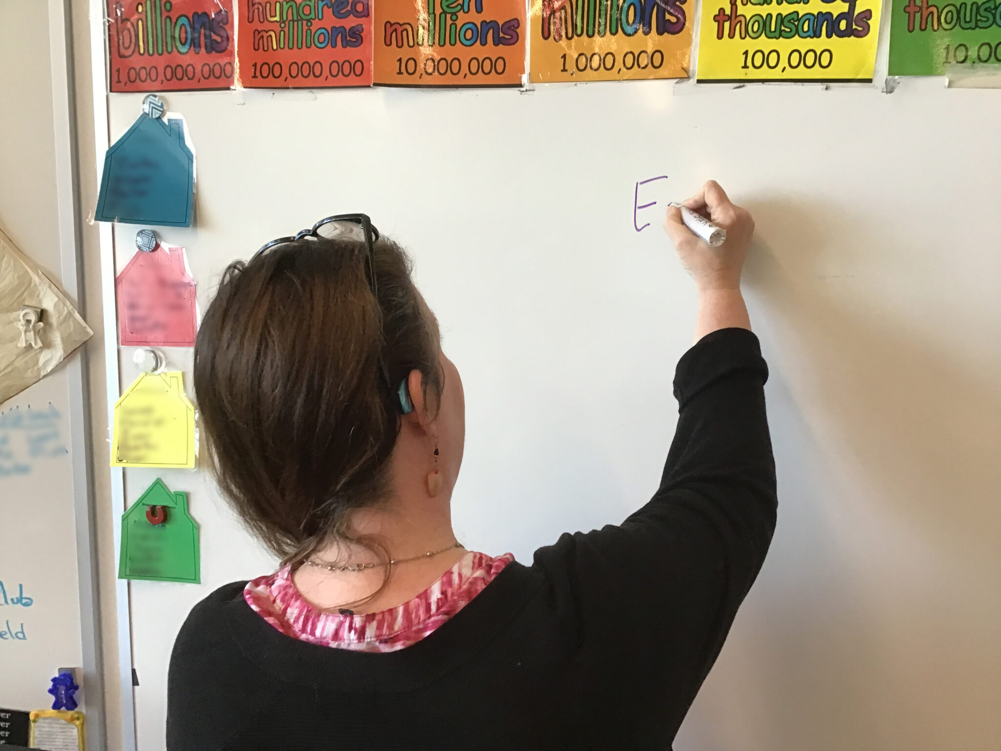 Rhonda writes with a marker on a dry erase board in her classroom..