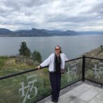 Lisa standing on a balcony overlooking a scenic body of water.