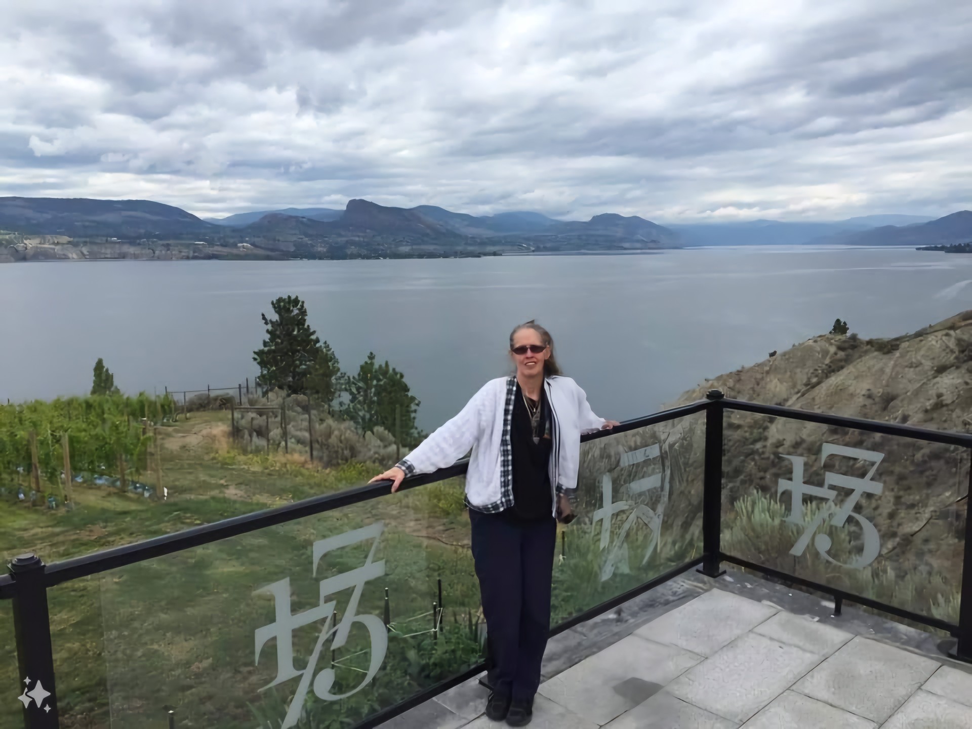 Lisa standing on a balcony overlooking a scenic body of water.